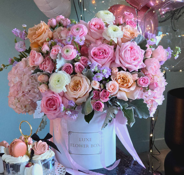 Coquette Arrangement featuring garden roses, ranunculus, Dusty Miller foliage, and other delicate blooms, elegantly arranged in a round box.