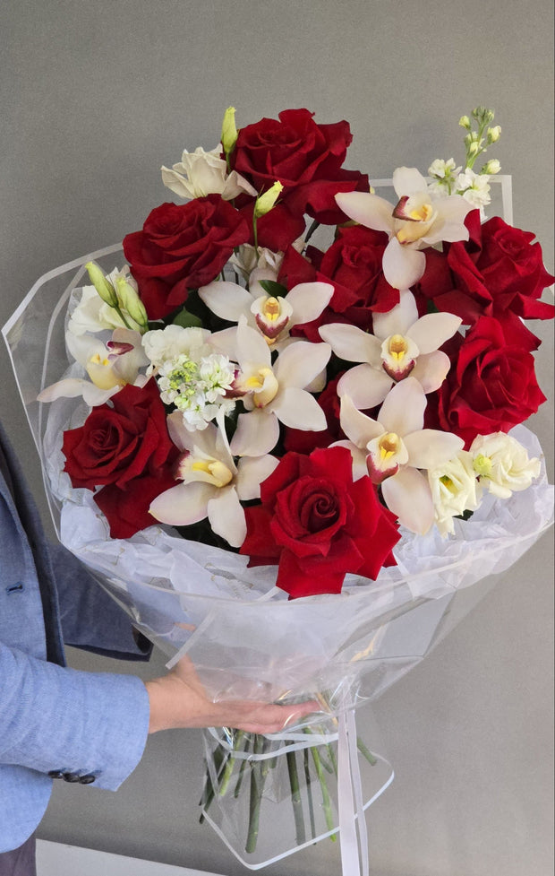 Elegant "Flame & Grace" arrangement featuring vibrant red roses and delicate white orchids, symbolizing passion and elegance in perfect harmony.