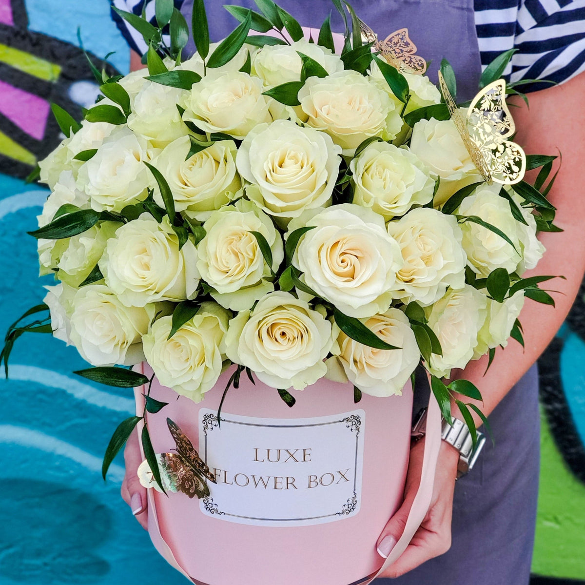 Elegant flower box arrangement featuring lush roses complemented by fresh greenery, creating a timeless and sophisticated floral display.