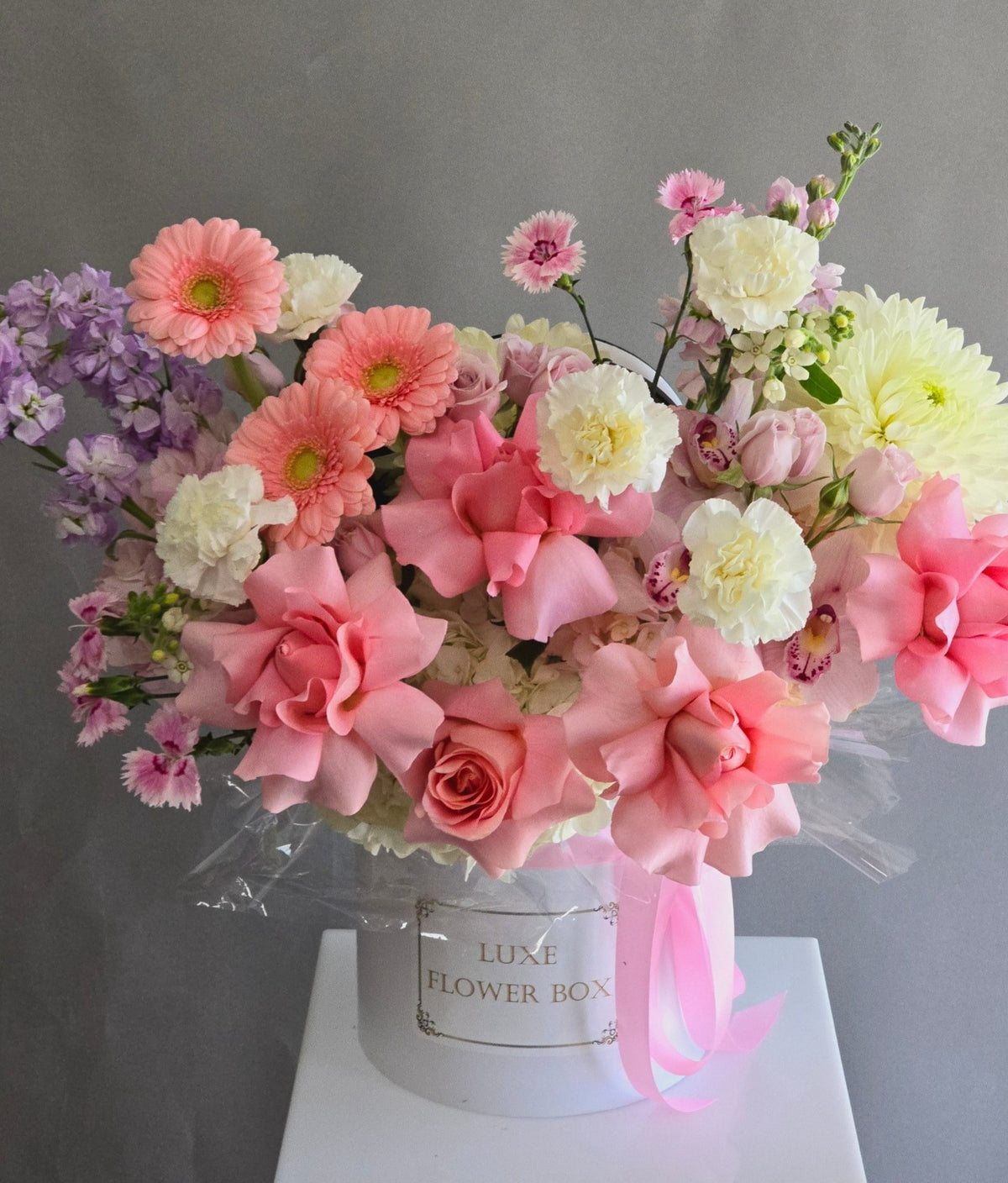 Lovely Pink Flower Box featuring orchids, gerberas, reflexed roses, and a touch of stock in soft pink and pastel tones