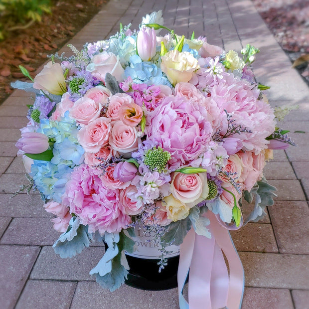 Paradise Arrangement in a round box featuring roses, peonies, lisianthus, Dusty Miller foliage, and other delicate blooms