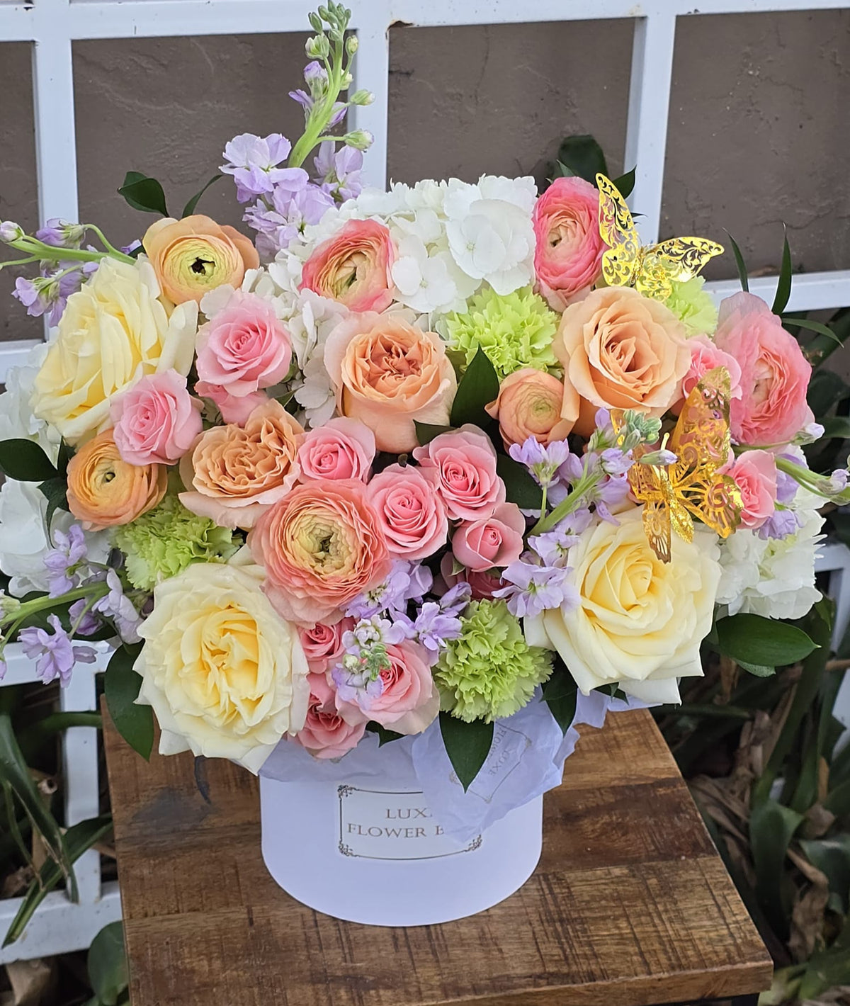 Flower box with elegant roses and ranunculus, featuring lush blooms in a beautifully arranged design.