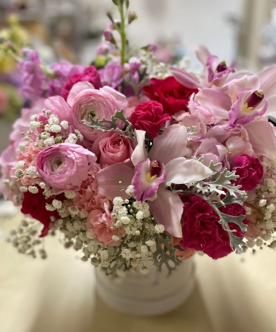 A stunning flower box featuring an array of pink blooms, including elegant roses, delicate orchids, and lush ranunculus, beautifully arranged to celebrate grace and femininity.