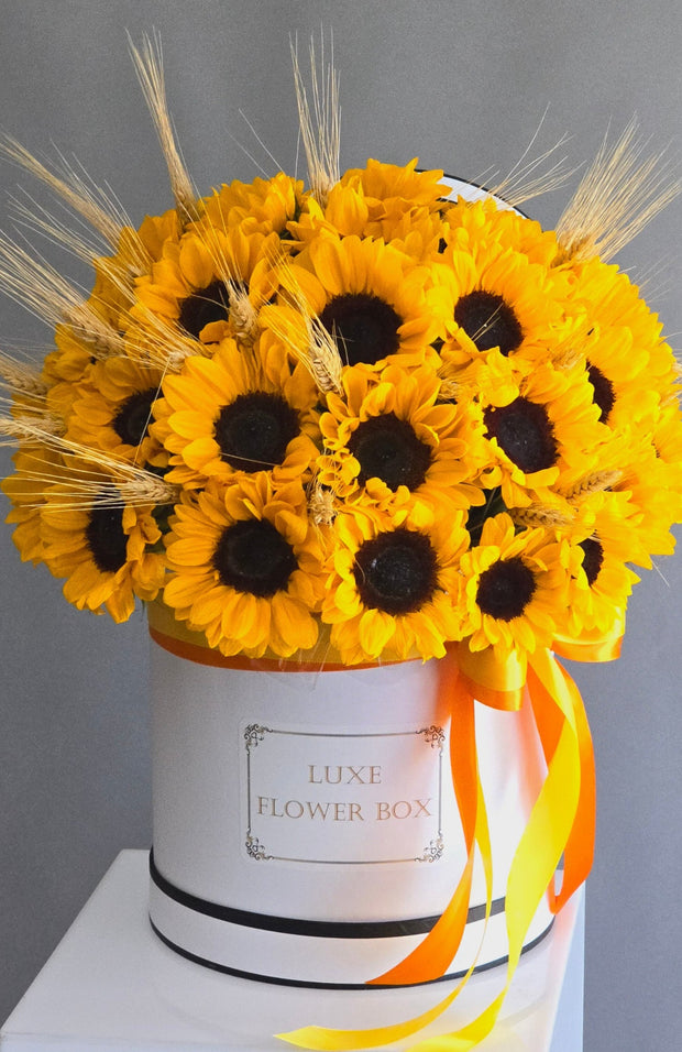 A rustic bouquet featuring vibrant yellow sunflowers paired with golden wheat stalks, creating a warm and earthy arrangement perfect for autumn or a country-inspired setting.