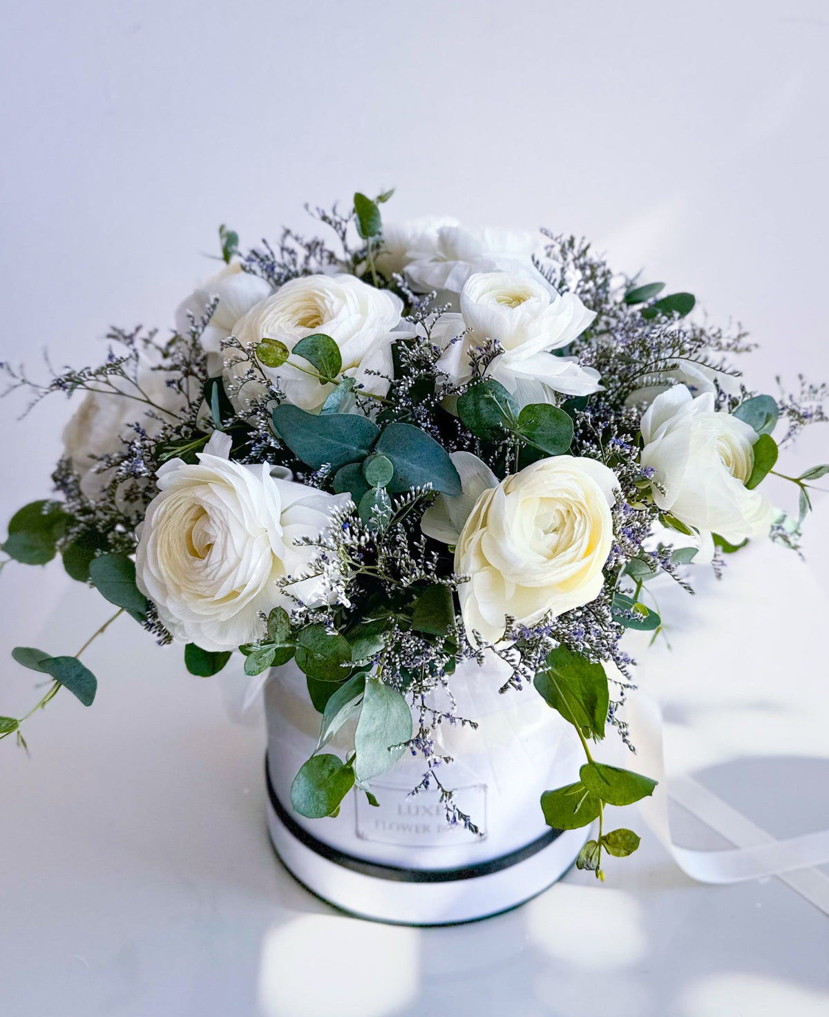 Round box arrangement featuring white anemones and eucalyptus for a clean and elegant design